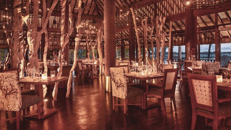 hotels in heaven four seasons bora bora culinary restaurant wooden floor chairs tables columns lights candles dishes dining
