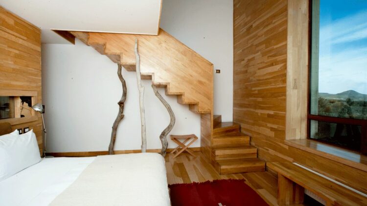 hotels in heaven tierra patagonia room bedroom view wooden floor stairs wood lamps bed white pillows window sky