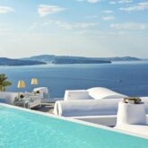 hotels in heaven katikies greece pool view terrasse luxury couch outside lamp view sea oat hill blue water sky clouds palm tree pillow